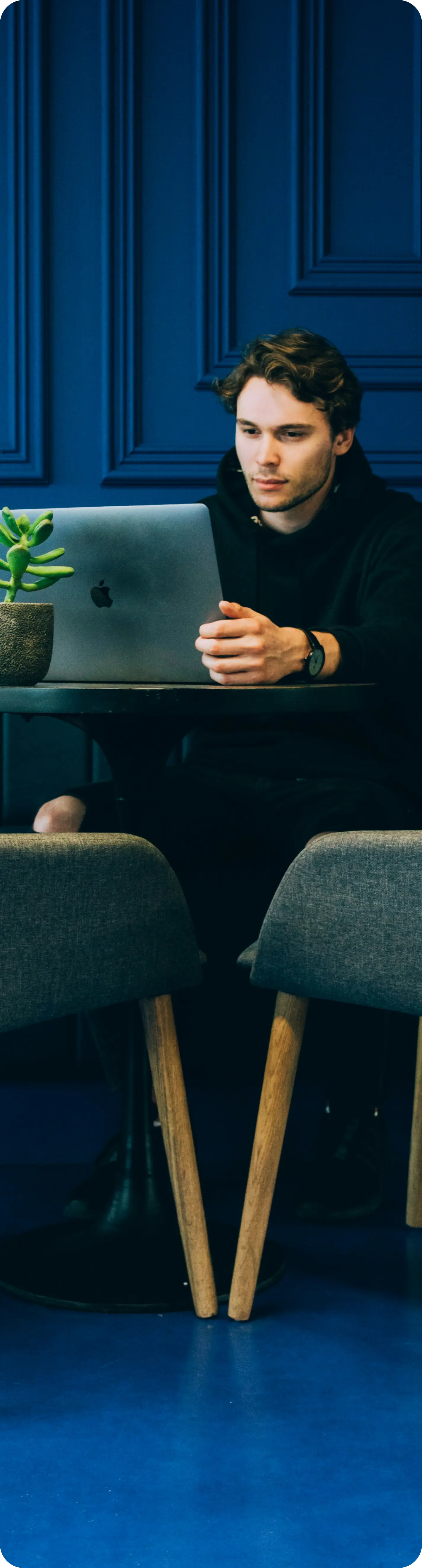 Center of the image showing the man sitting at the table working on a computer